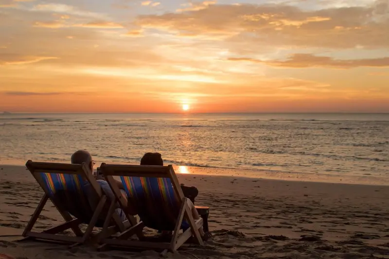Deux transats sur une plage au coucher du soleil.