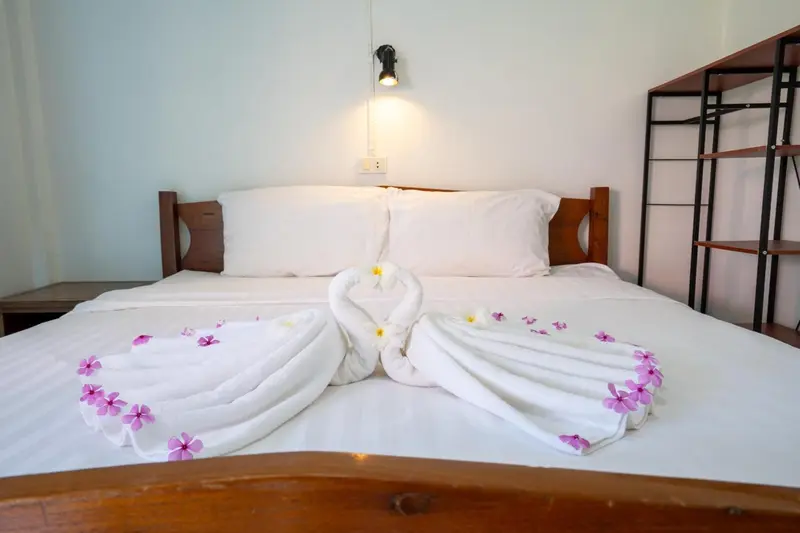 Une chambre lumineuse avec un lit double décoré de serviettes en forme de cygnes.