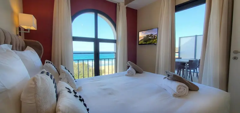 Une chambre lumineuse avec un grand lit donnant sur une vue mer.