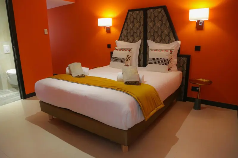 Une chambre aux murs orange et au lit recouvert d'une courtepointe.