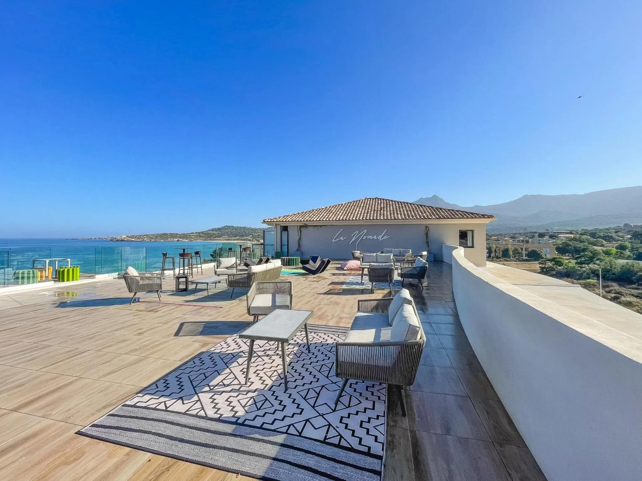 Terrasse aménagée avec mobilier de jardin et vue sur la mer.