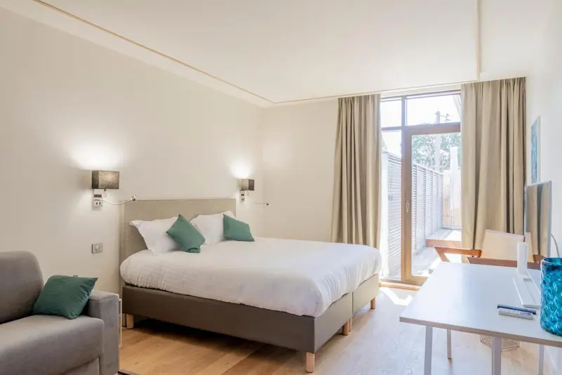 Une chambre lumineuse avec un grand lit et un accès à une terrasse.