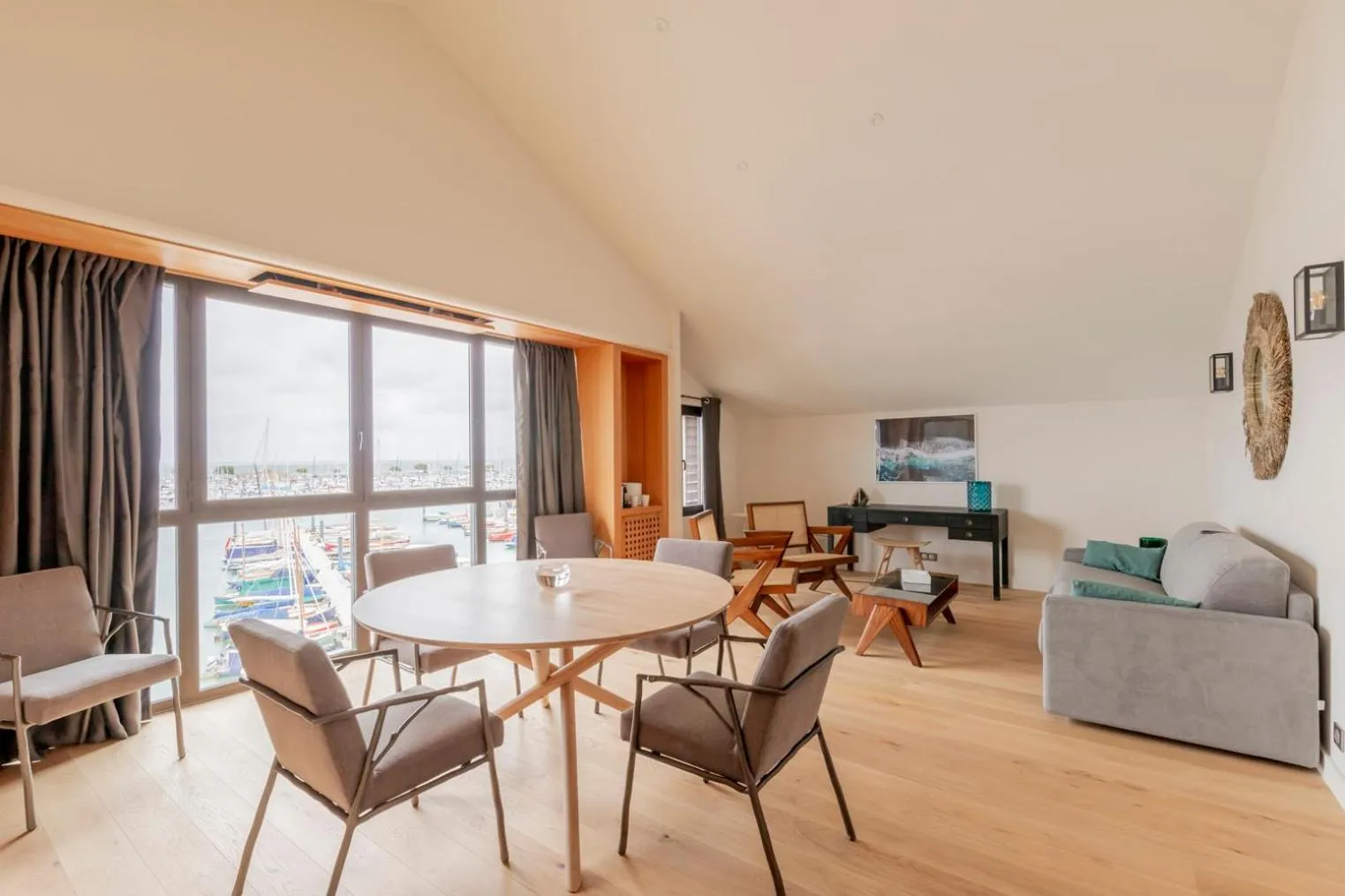Espace de vie lumineux avec table à manger et canapé près d'une grande fenêtre.