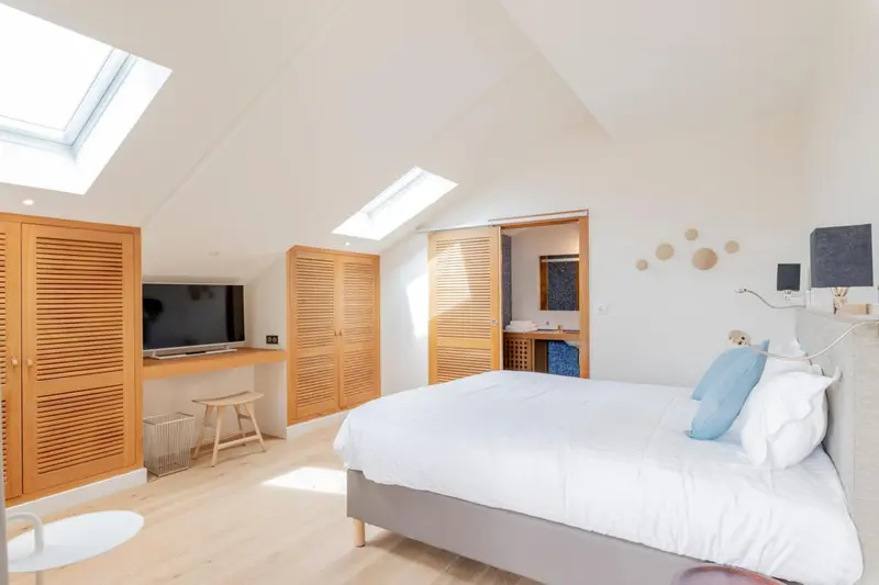 Une chambre lumineuse avec un lit et un meuble télévision.