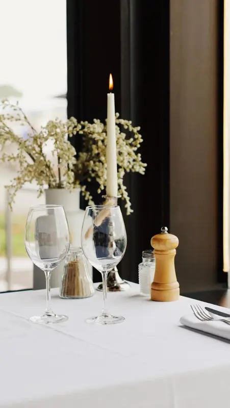 Table dressée avec des verres, une bougie et des condiments.