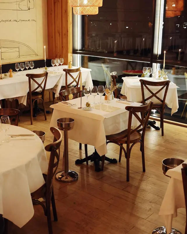 Une salle de restaurant avec des tables dressées et des chaises en bois.