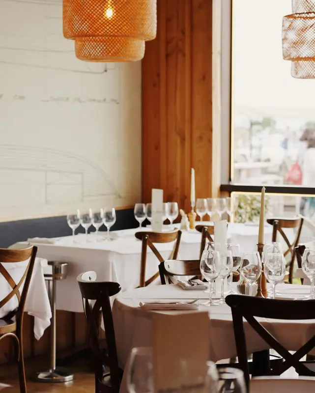 Une salle lumineuse avec des tables dressées pour un repas.