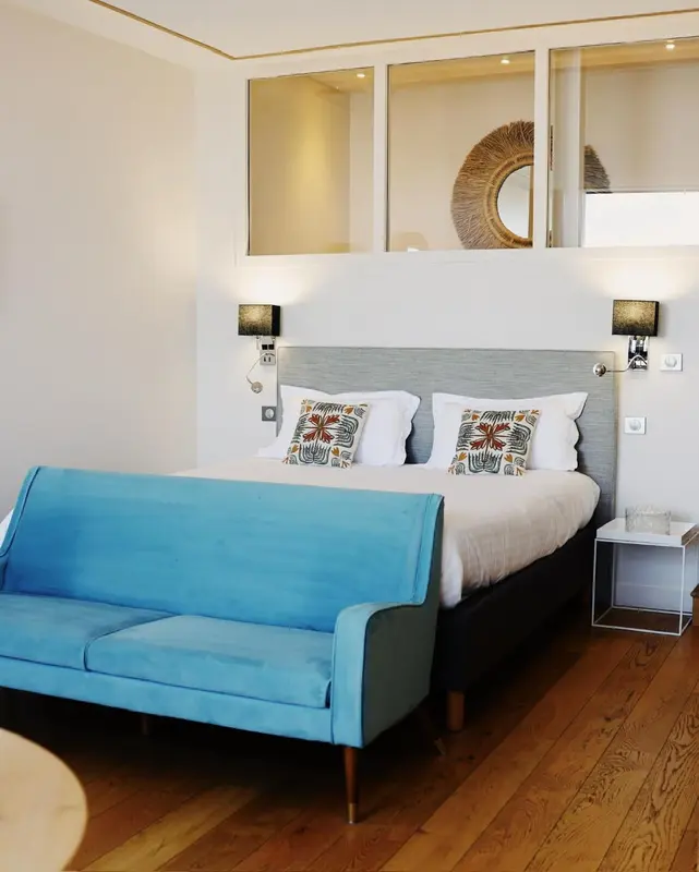 Une chambre lumineuse avec un canapé bleu et un grand lit.