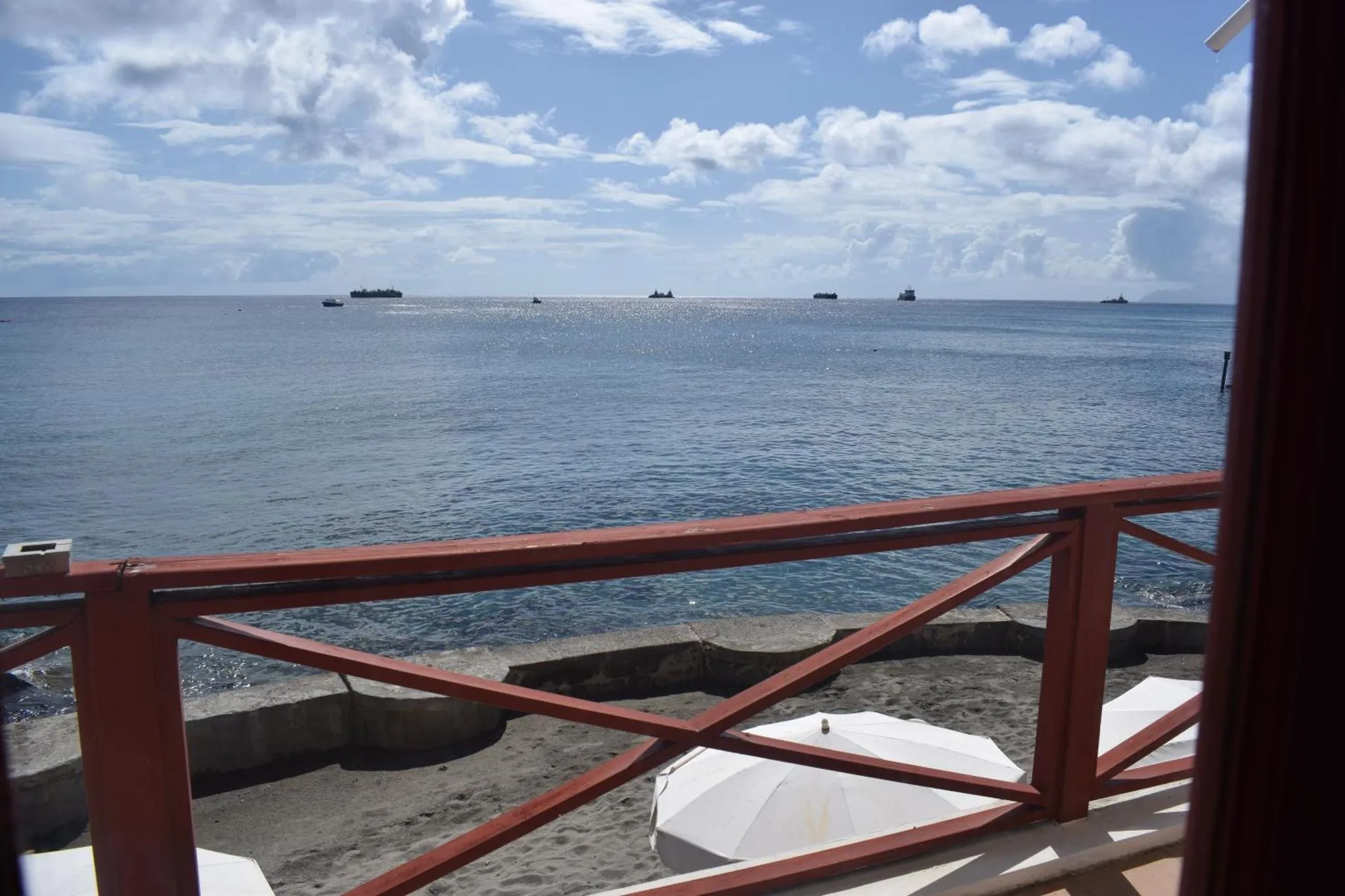 Vue sur la mer depuis une terrasse avec une rambarde rouge.