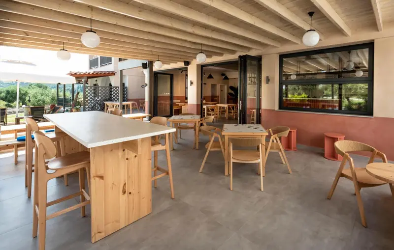 Terrasse ombragée avec tables et chaises en bois.