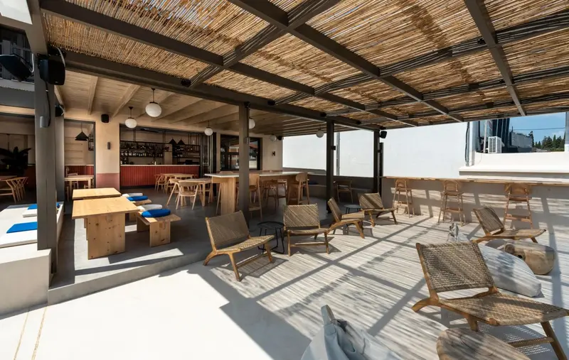 Espace de détente extérieur avec mobilier en bois et bar en fond.