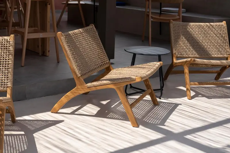 Des fauteuils en rotin sont disposés sur une terrasse ombragée.