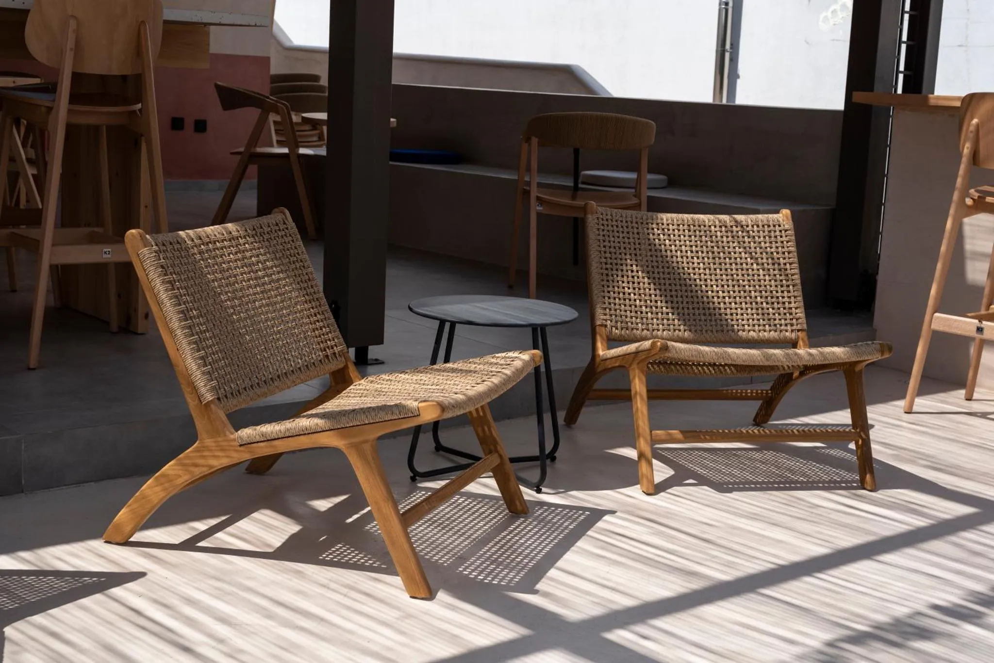 Deux fauteuils en osier sur une terrasse ombragée.