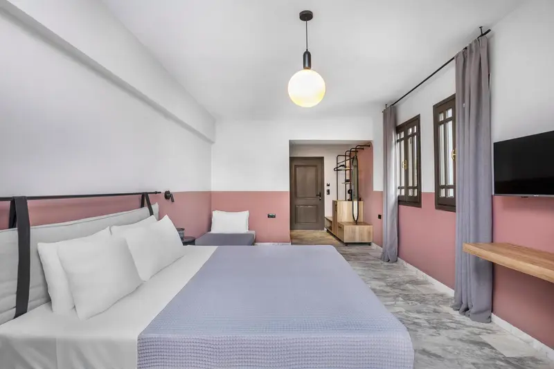 Chambre lumineuse avec un lit double et un mur bicolore.