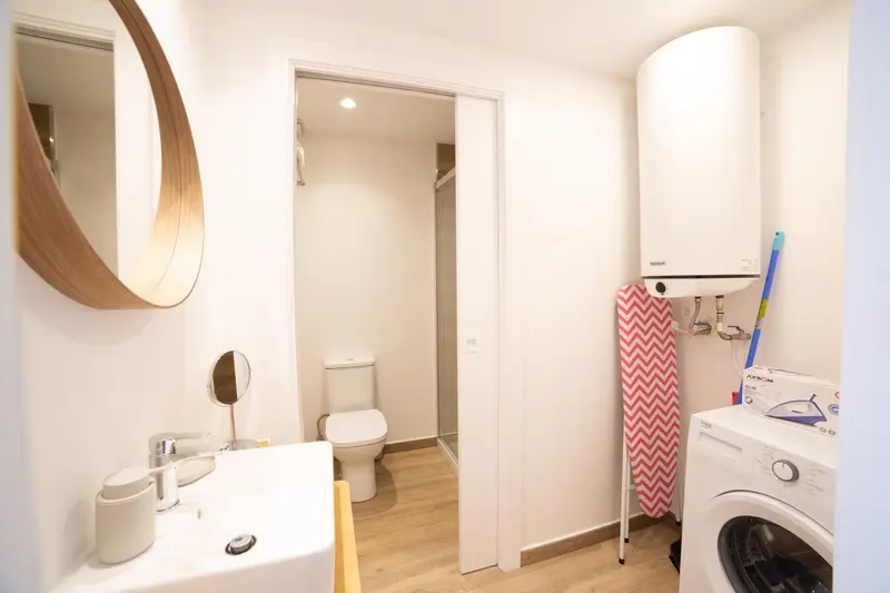 Une salle de bain claire avec un lavabo, des toilettes et un lave-linge.