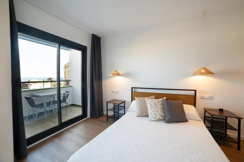 Une chambre lumineuse avec un lit et un accès à un balcon.