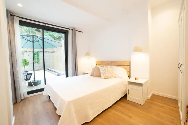 Une chambre lumineuse avec un grand lit et un accès à une terrasse.