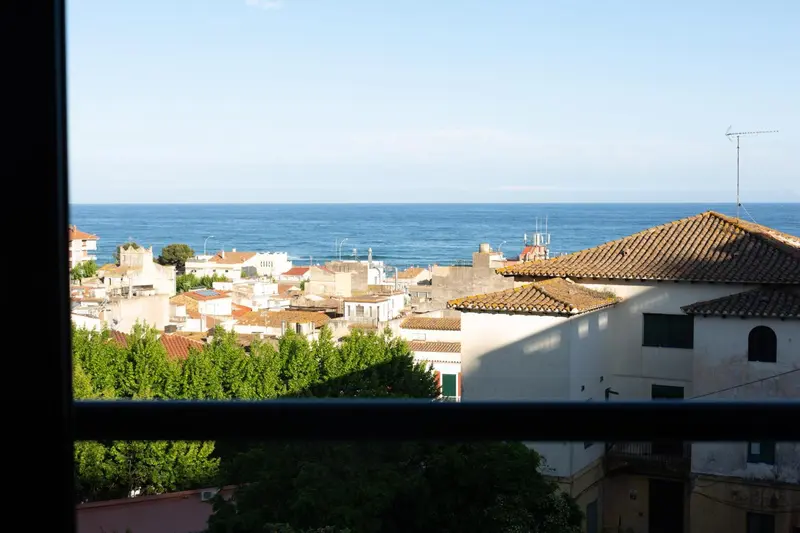 Vue sur la mer et les toits d'une ville ensoleillée.