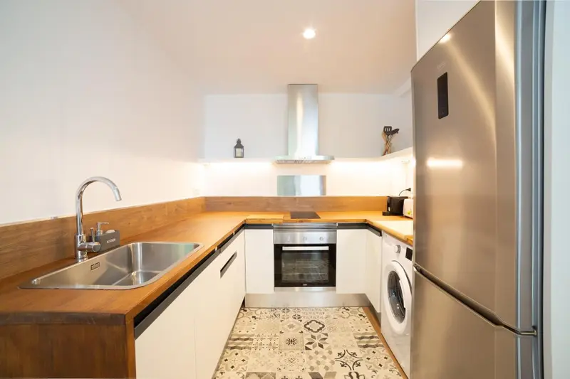 Une cuisine moderne avec un plan de travail en bois et des appareils électroménagers blancs.