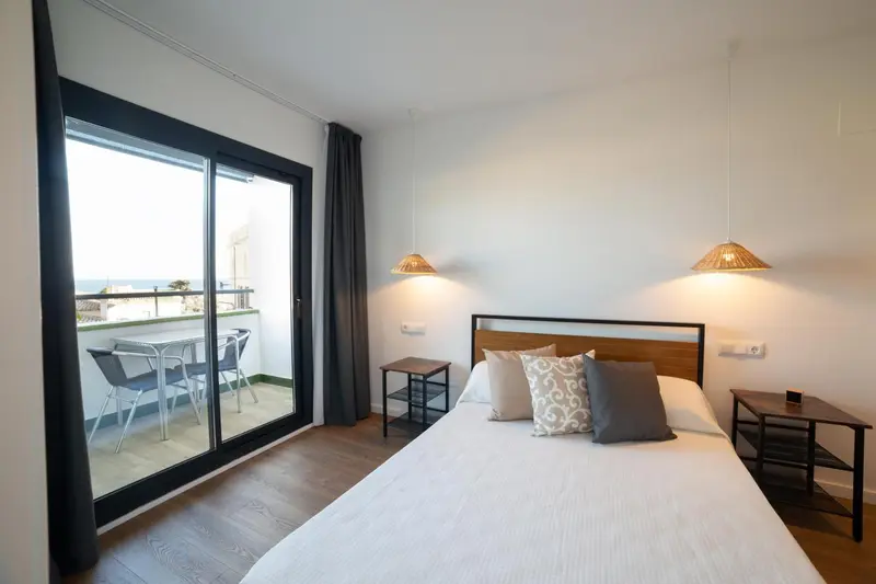 Une chambre lumineuse avec un grand balcon donnant sur la mer.