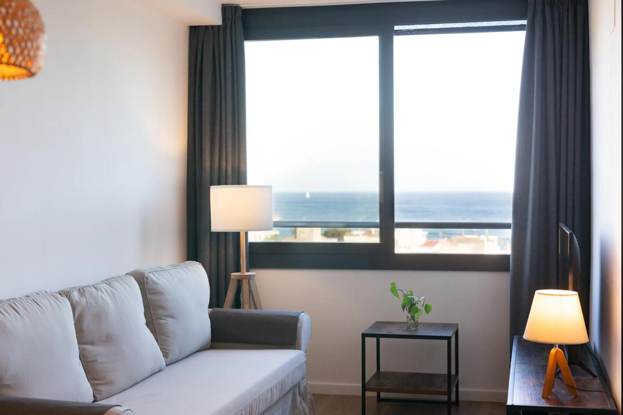 Espace de détente lumineux avec canapé et vue sur la mer.