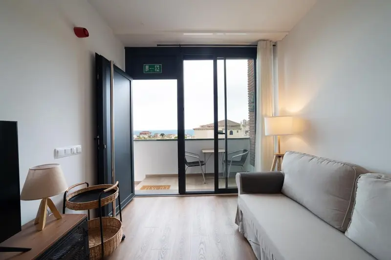 Espace de vie lumineux avec canapé et accès à une terrasse vue mer.