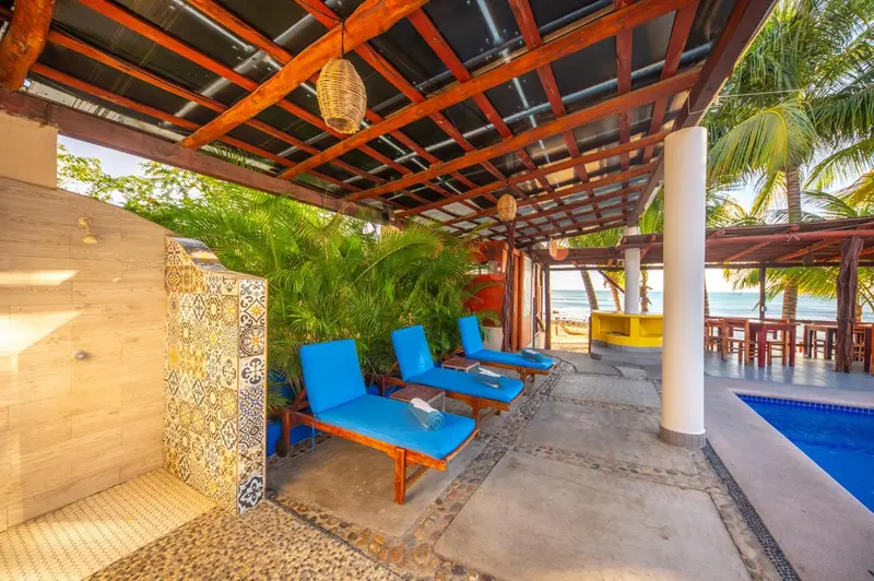 Espace de détente extérieur avec chaises longues et douche à l'air libre.