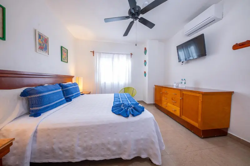 Une chambre lumineuse avec un grand lit et une commode en bois.