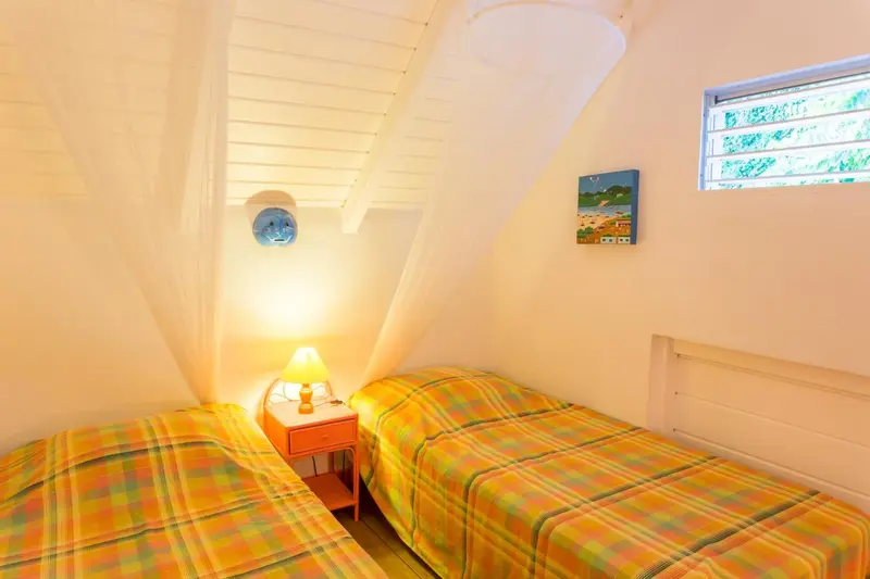 Une chambre lumineuse avec deux lits simples et une décoration colorée.