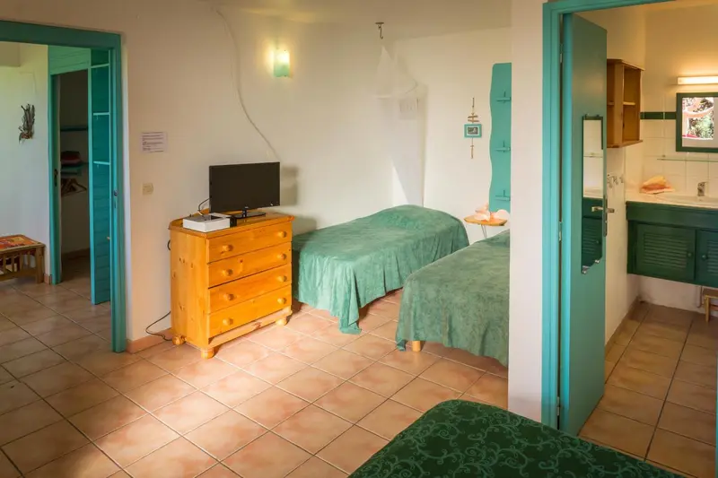 Une chambre lumineuse avec deux lits simples et une commode en bois.