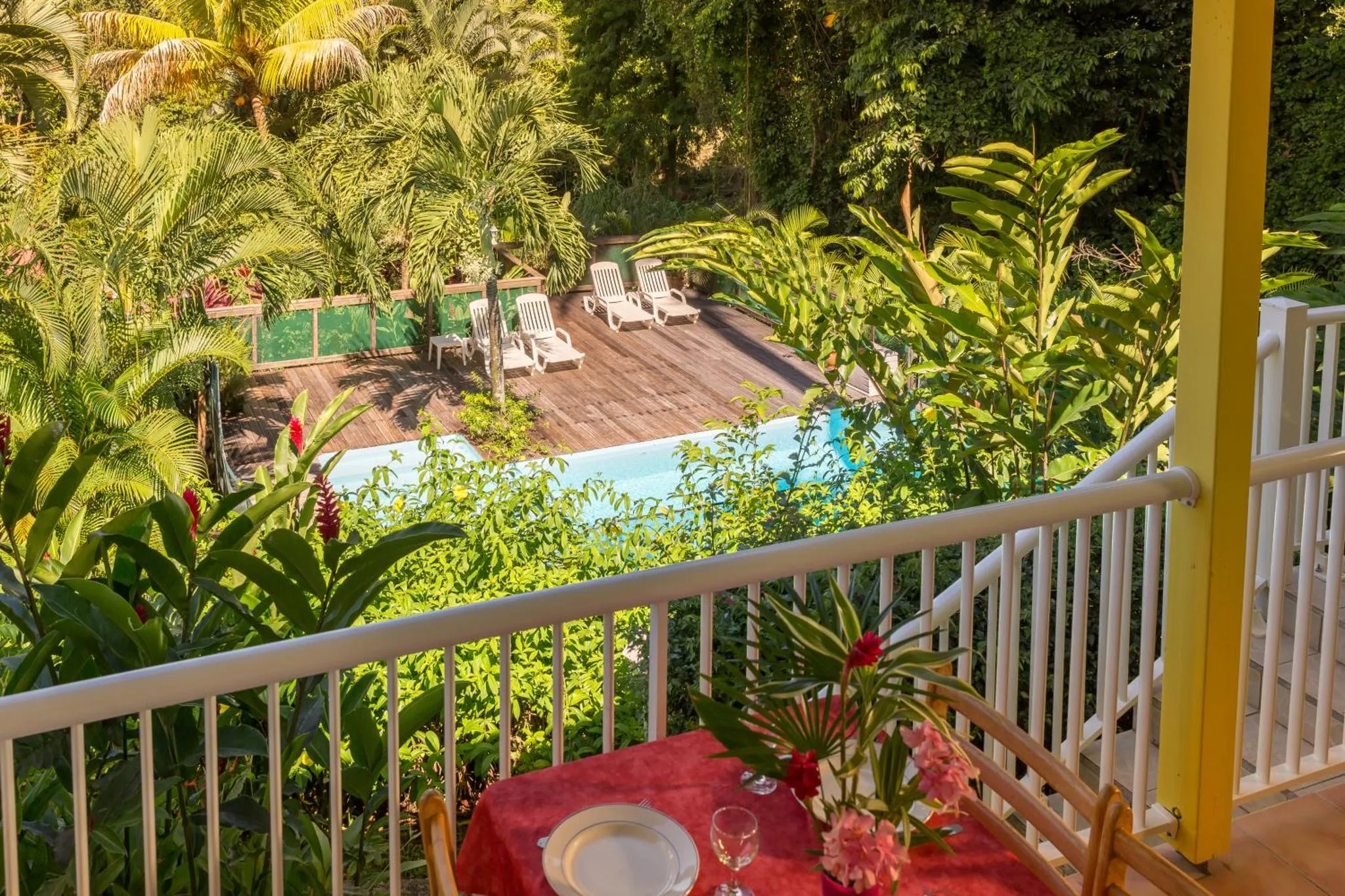Terrasse avec table et chaises donnant sur une piscine et des transats.