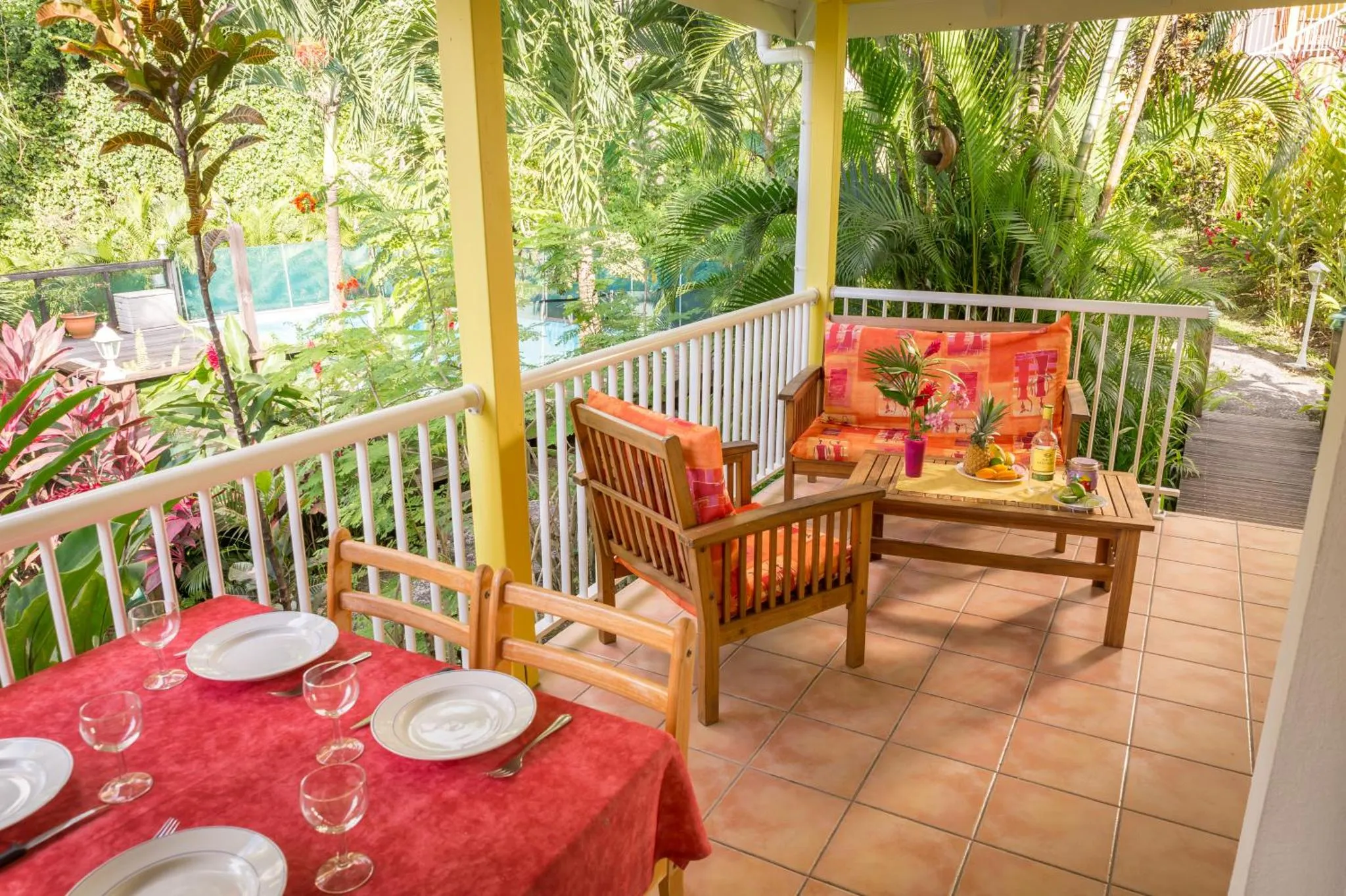 Une table est dressée sur une terrasse ombragée avec vue sur la végétation.