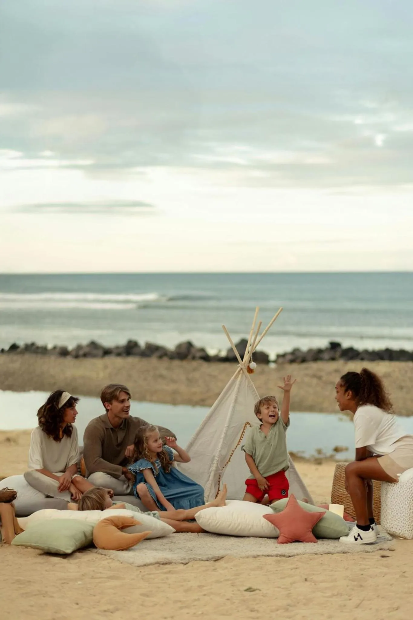 Une famille se détend sur une plage de sable fin face à la mer.