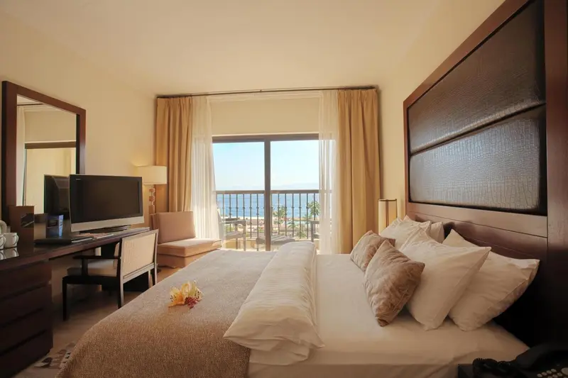 Chambre lumineuse avec un grand lit et vue sur la mer.