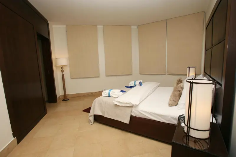 Une chambre lumineuse avec un grand lit et des rideaux beiges.