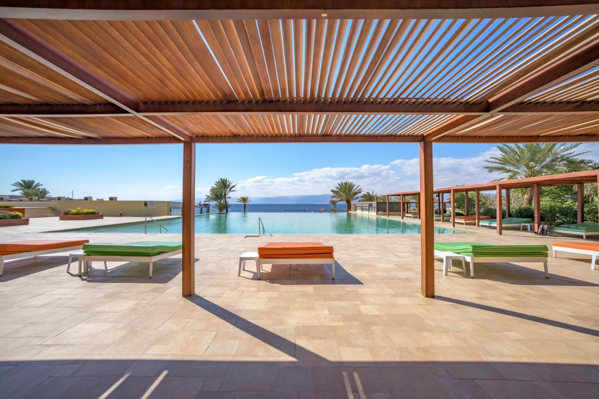 Terrasse avec transats et piscine à débordement donnant sur la mer.