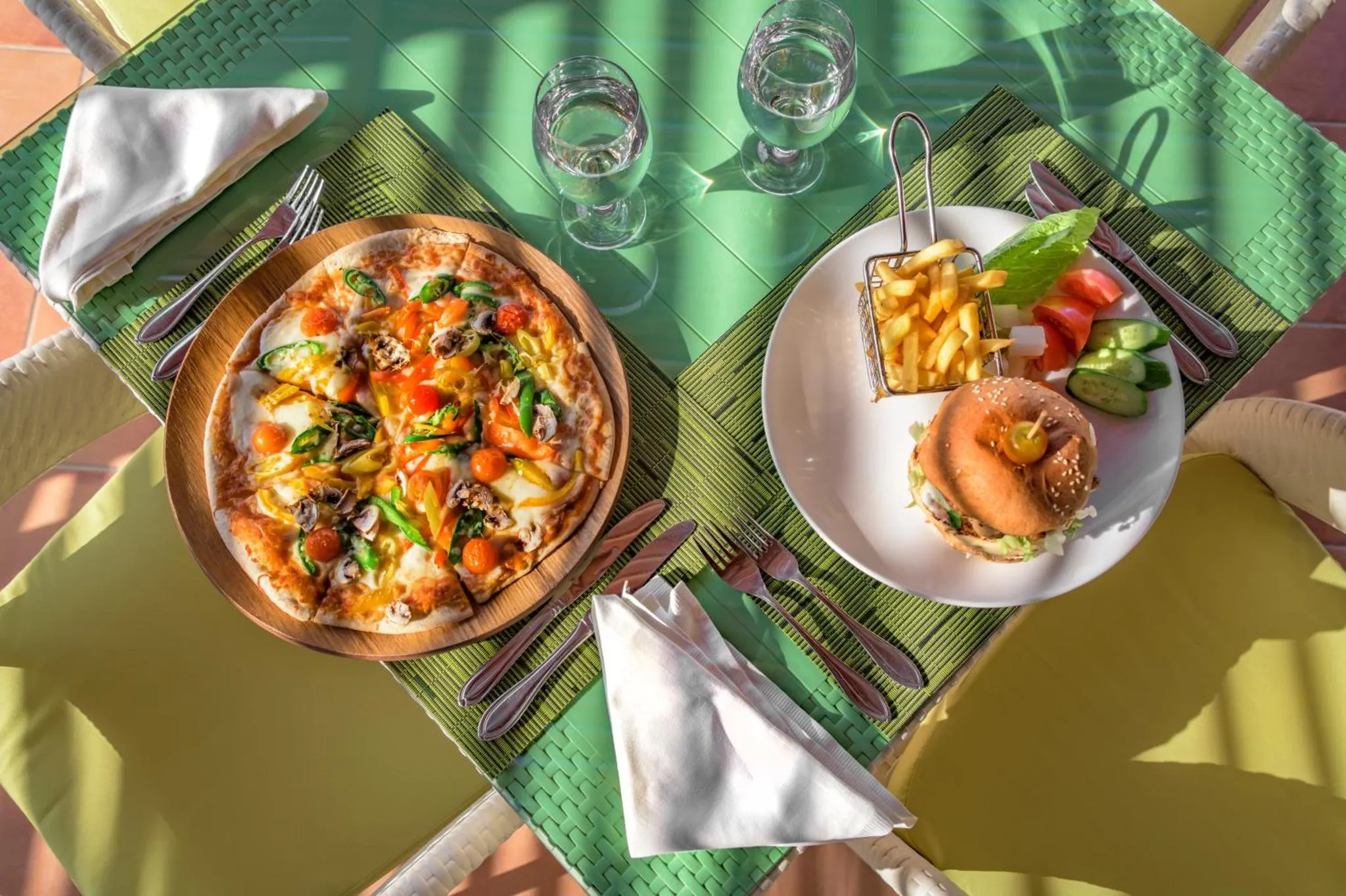 Une table est dressée avec une pizza, des frites et un hamburger.