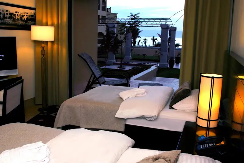 Une chambre lumineuse avec deux lits et un accès à une terrasse.