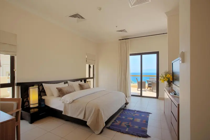 Chambre lumineuse avec un grand lit et une vue sur la mer.