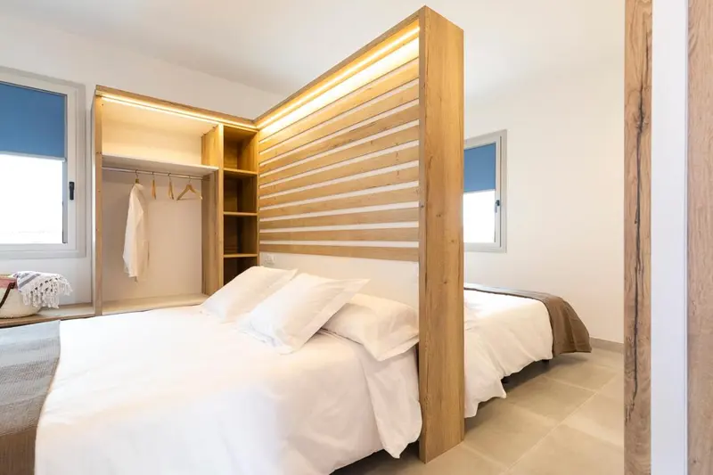 Une chambre lumineuse avec un grand lit et une tête de lit en bois décorative.