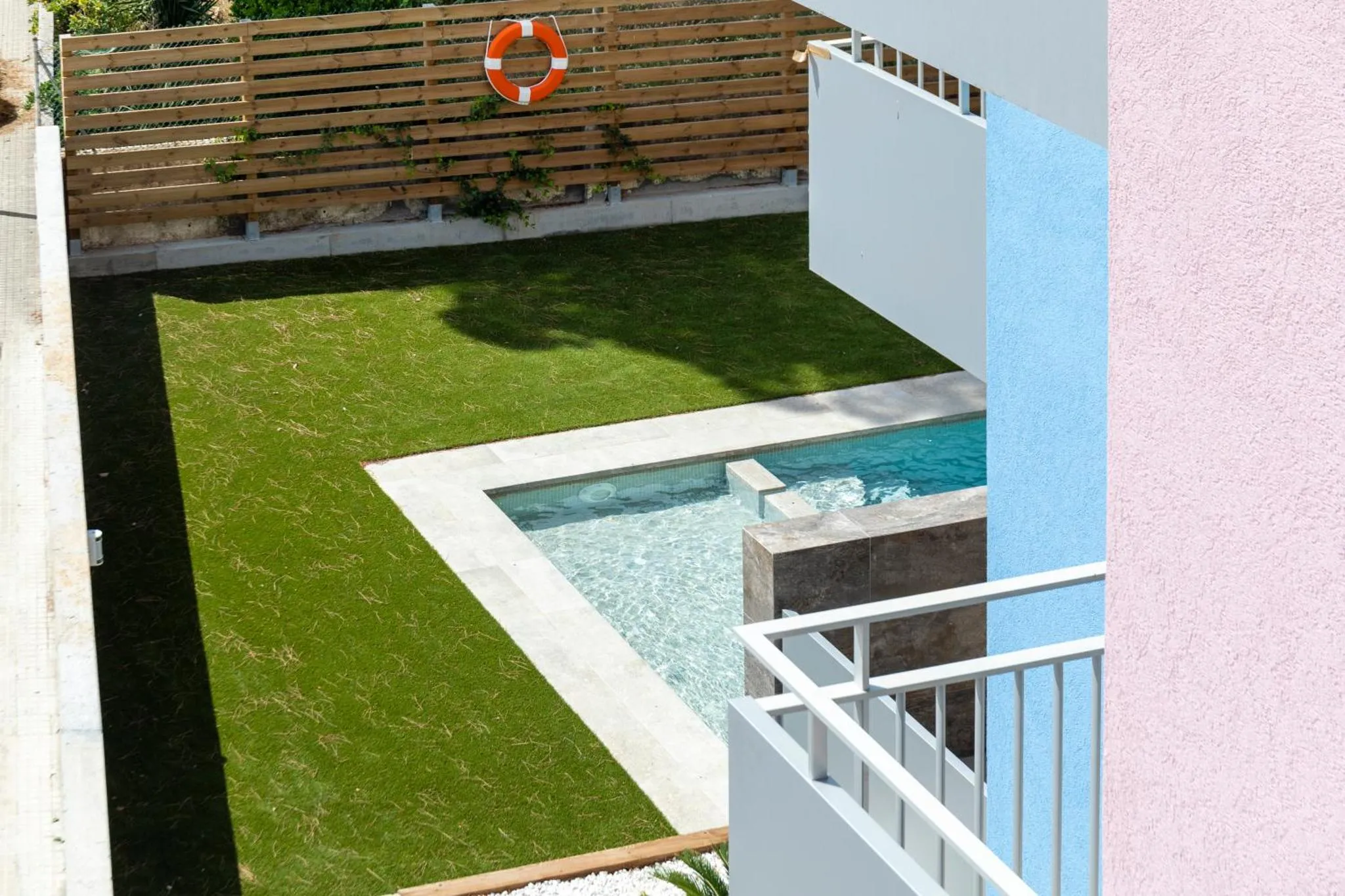 Une petite piscine rectangulaire est entourée d'une pelouse verte et d'une terrasse.
