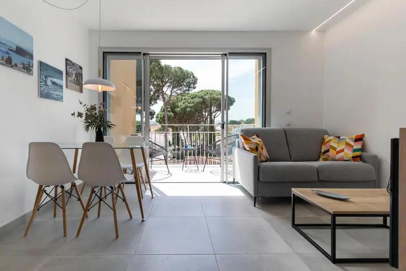 Espace de vie lumineux avec canapé, table à manger et accès à une terrasse.