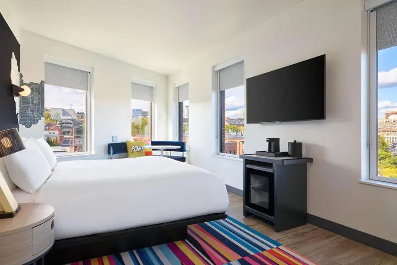 Une chambre lumineuse avec un grand lit et une vue sur la ville.
