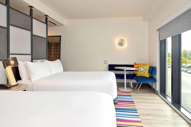 Une chambre lumineuse avec un grand lit et un coin salon près d'une fenêtre.