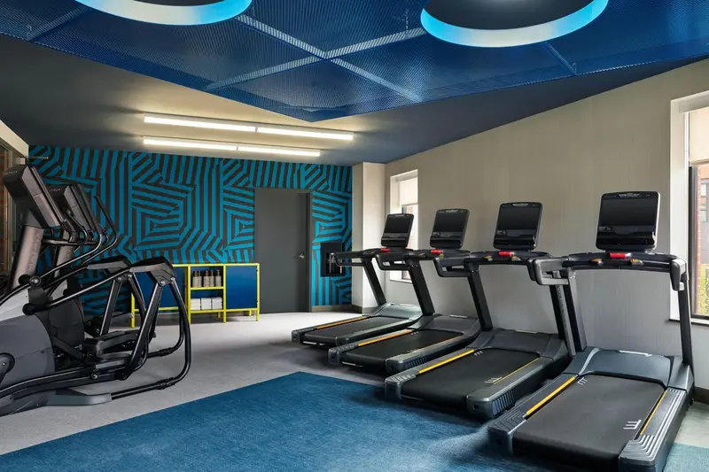 Une salle de sport lumineuse avec plusieurs appareils de cardio.