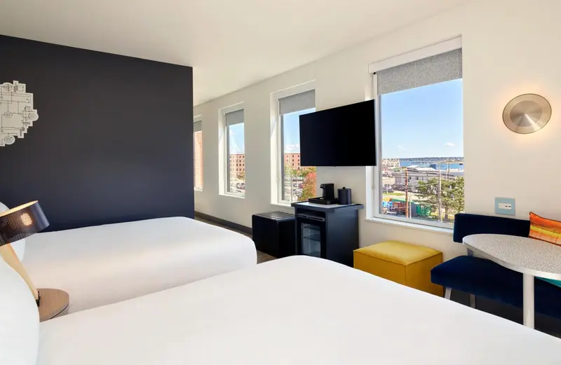 Une chambre lumineuse avec un lit double et une vue sur la ville.