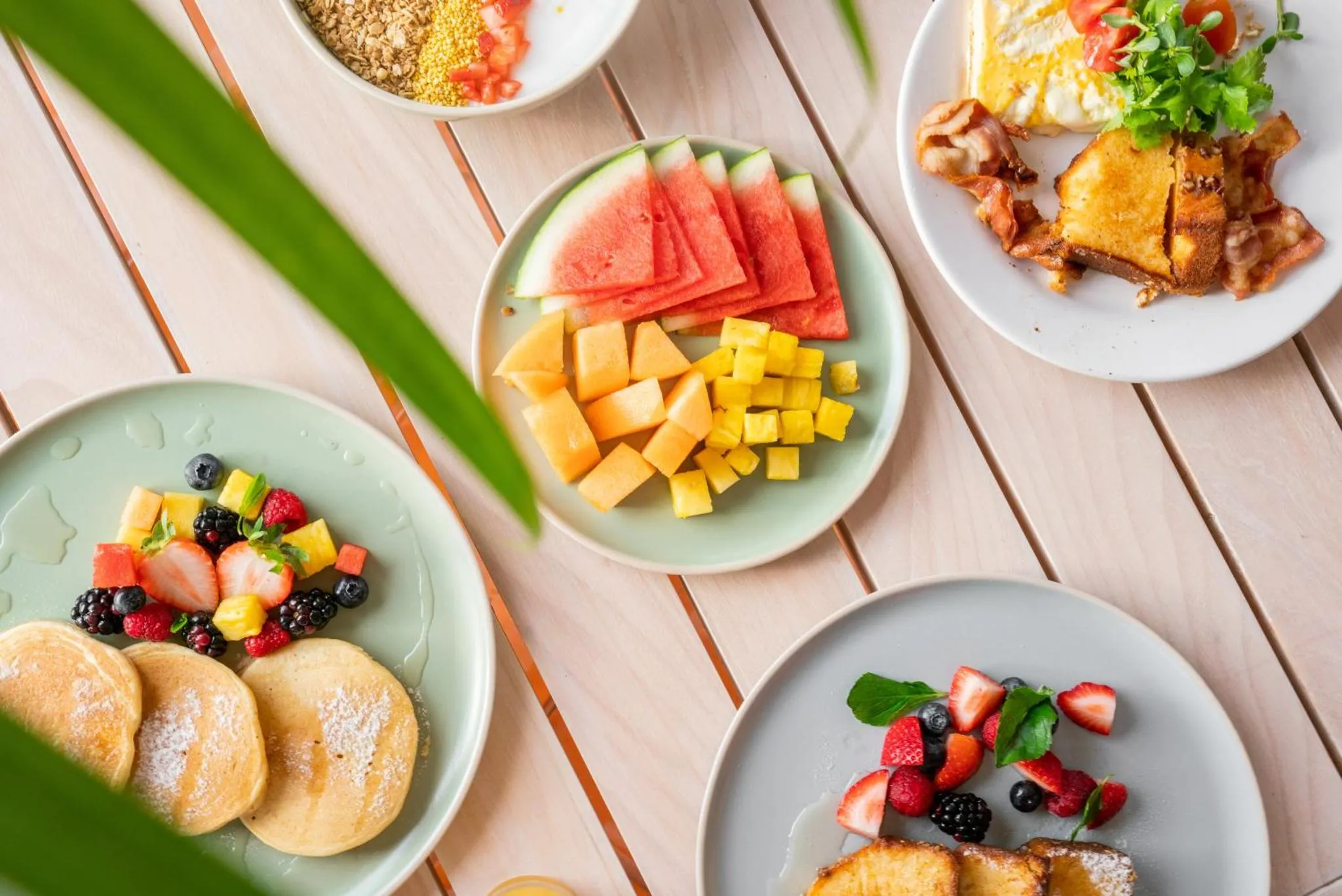 Assortiment de fruits frais et de plats sucrés servis sur des assiettes colorées.