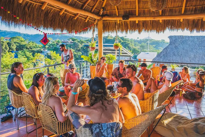 Un groupe de personnes est assis et discute sur une terrasse couverte.
