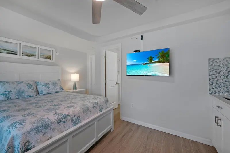 Une chambre lumineuse avec un grand lit et une télévision murale.