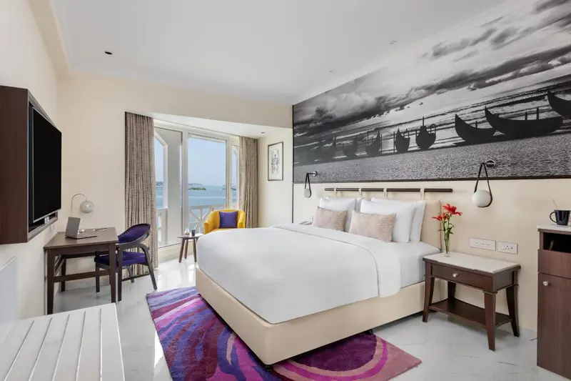 Chambre lumineuse avec un grand lit et une vue sur la mer.